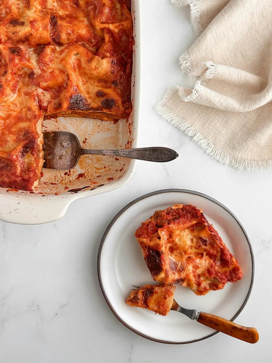 Lasagne in der Auflaufform, ein Stück auf dem Teller